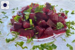 Balsamic Beet Salad On A Glass Serving Dish With Parsley Scattered Around.