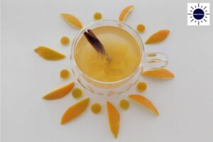 Orange Drink With A Cinnamon Stick In A Glass Mug With An Orange Peel Flower Decoration Around It.