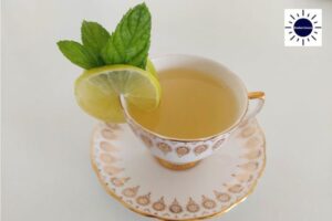 Mint Lime Brew In A Decorative Teacup Adorned With Fresh Lime And Mint On A Small Plate.