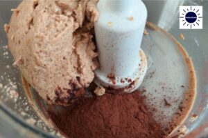 Cocoa Powder And Maple Syrup Added To Food Processor.