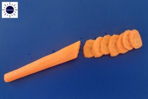 Carrot Cut Into Thin Oval Shapes On Cutting Board.