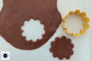 Scalloped Circle Cut From Dough With The Cookie Cutter On The Side.