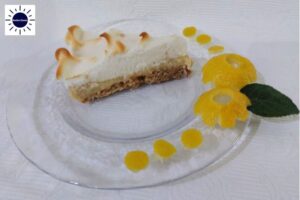 A Slice Of Pie On A Glass Plate With Two Lemon Peel Flowers On The Side For Decoration.