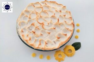 Wholegrain Honey Lemon Meringue Pie In A Glass Pie Dish Decorated On The Side With Two Lemon Peel Flowers That's Suited For Dessert In A Decorative Circle Adorned With Two Graphic Hearts On The Side.