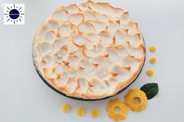 Wholegrain Honey Lemon Meringue Pie In A Glass Pie Dish Decorated On The Side With Two Lemon Peel Flowers.