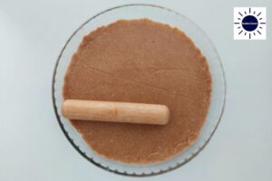 Smoothing Out The Edges Of The Pie Crust Within The Pie Dish With A Small Rolling Pin.