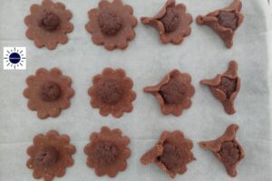 The Dough Circles With Filling In The Center On A Baking Sheet Showing The Steps To Make The Hamantashen.