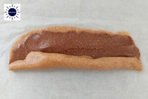 First Roll Of Cookie Dough Oblong Shape With Filling. On Baking Sheet.