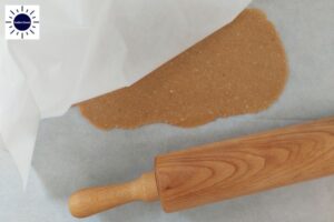 Oblong Shape Of Cokkie Dough Rolled Out Between Two Baking Sheets With Rolling Pin.