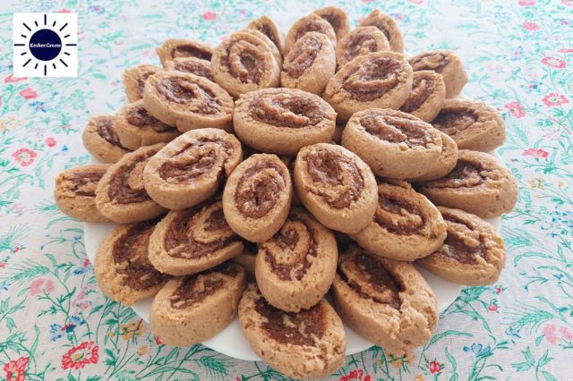 Wholegrain Almond Cinnamon Swirl Cookies Arranged Like A Flower On A Serving Plate On Top Of A Flowered Tablecloth.