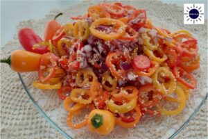 Mediterranean Sesame Mini Peppers Salad On A Serving Dish Decorated With A Few Mini Peppers On A Lace Cloth With The Kosher Create Sun Logo In The Upper Right Corner.