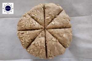 The Ball Of Dough Cut Acroos Four Times With Even Spaces Between Them And With The Kosher Create Sun Logo In The Upper Left Corner.