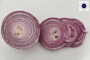 A Red Onion Partially Sliced On A Cutting Board.