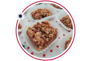 Wholegrain Strawberry Peanut Butter Bars In Cup Cake Holders Spread Out On A Doted Cloth That’s Suited For Breakfast Within A Decorative Circle Adorned With The Kosher Create Sun Logo.
