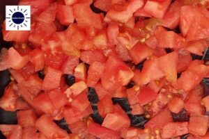 A Closeup Of Cubed Tomatoes In A Nonstick Frying Pan With The Kosher Create Sun Logo In The Upper Left Corner.