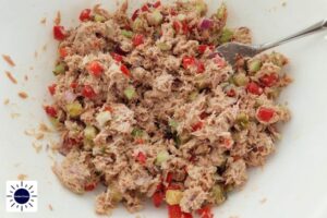 A Closeup Of Cubed Vegetables Mixed Into The Tuna And With The Kosher Create Sun Logo In The Left Bottom Corner.