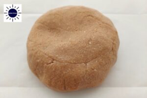 A Ball Formed From The Pranut Butter Dough On A Baking Sheet With The Kosher Create Sun logo In The Upper Left Corner.
