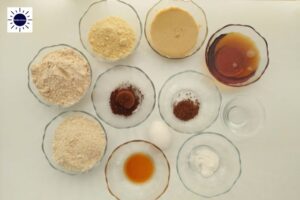 Wholegrain Cocoa Maple Mocha Cookies Ingredients In Glass Bowls Arranged In A Circular Fashion With The Kosher Create Sun Logo In The Upper Left Corner.