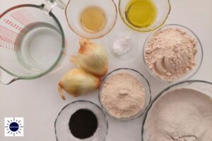 Wholegrain Vegan Onion Soda Bread Rolls Ingredients Arranged In Glass Utensils And With The Onions In Between And With The Kosher Create Sun Logo In The Left Lower Corner.