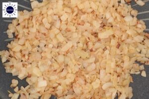 A Closeup Of Cubed Onions Sauteed Till Golden Brown With The Kosher Create Sun Logo In The Upper Left Corner.