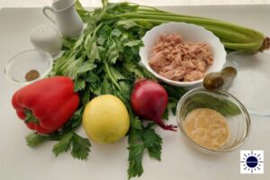 Mediterranean No-Mayo Dairy-Free Tuna Salad Ingredients Displayed On A Table With The Tuna Dressing And Pepper And Pickle In In A Glass Bowls And The Olive Oil In A Small Pitcher And With The Kosher Create Sun Logo In The Bottom Right Corner.