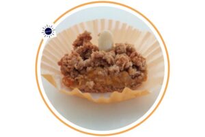 A Wholegrain Almond Fresh Apricot Bar Within A Decorative Cupcake Holder That’s Suited For Breakfast Within A Decorative Circle Adorned With The Kosher Create Sun Logo.