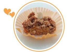 A Wholegrain Almond Fresh Apricot Bar Within A Decorative Cupcake Holder Within A Decorative Circle That's Suited For Dessert In A Decorative Circle Adorned With Two Graphic Hearts On The Side.