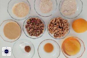 Mediterranean Wholegrain Pistachio Cookies Filling Ingredients In Glass Bowls Arranged In A Circle With The Kosher Create Sun Logo In The Lower Left Corner.