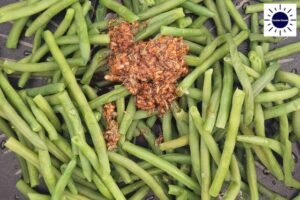 A Closeup Of The Dressing Mixture On The Green Beans With The Kosher Create Sun Logo In The Upper Right Corner.