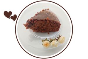 A Slice Of Mediterranean Wholegrain Orange Honey Cake On A Glass Plate With Three Small Roses Adorning In Front That's Suited For Dessert In A Decorative Circle Adorned With Two Graphic Hearts On The Side.