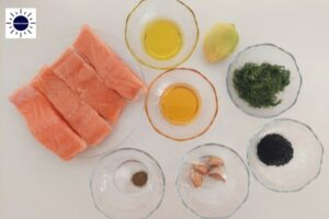 Mediterranean Baked Lemony Honey Salmon Ingredients Arranged In A Circle With The Kosher Create Sun Logo In The Upper Left Corner.