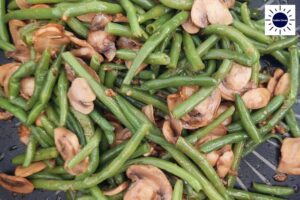 A Closeup Of The Mushroom And Green Bean Mixture After Sautéing With The Kosher Create Sun Logo In The Upper Right Side.
