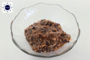 A Closeup Of Pesto Paste In A Glass Bowl With The Kosher Create Sun Logo In The Upper Left Corner.