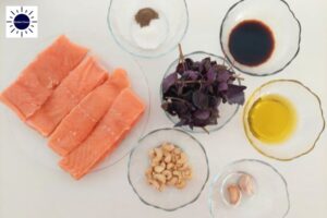 Mediterranean Baked Cashew Pesto Salmon In Glass Dishes With The Kosher Create Sun Logo In The Upper Left Corner.