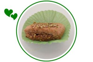 An Individual Mediterranean Wholegrain Pistachio Cookie On A Decorative Cupcake Holder That's Suited For Dessert In A Decorative Circle Adorned With Two Graphic Hearts On The Side.
