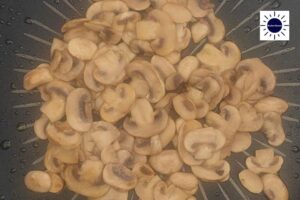 A Closeup Of Sauteed Sliced Mushrooms In A Frying Pan With The Kosher Create Sun Logo In The Upper Right Corner.