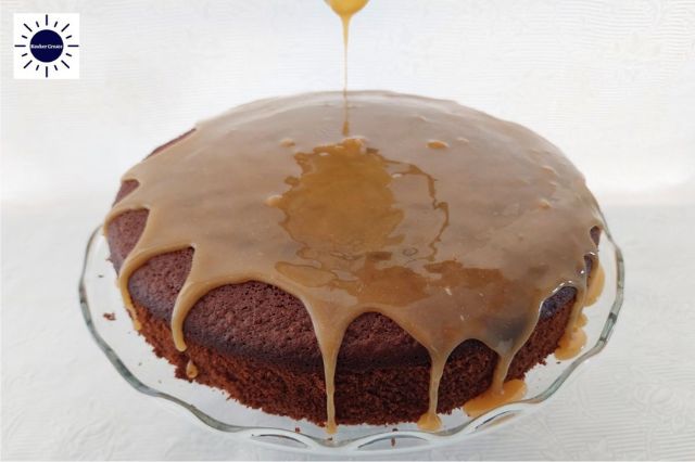 Honey Orange Glaze Dripping On A Cake On A Glass Cake Stand With The Kosher Create Sun Logo In The Upper Left Corner.