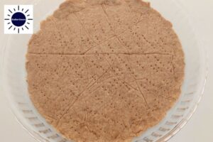 The Baked Crust In A Round Glass Pie Dish With The Kosher Create Sun Logo In The Upper Left Corner.