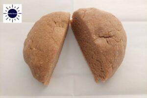 A Closeup Of The Ball Of Dough Divided In Half With The Kosher Create Sun Logo In The Upper Left Corner.