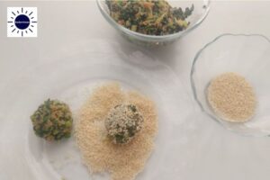 A Ball Formed From The Chard Mixture And Coated On All Sides With Sesame Seeds With The Kosher Create In The Upper Left Corner.
