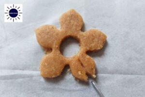 A Vee Cut Into The Cookie Flower Form With The Kosher Create Sun Logo In The Upper Left Side.