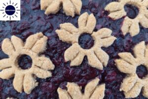 A Closeup Of The Arranged Cookie Flowers On top Of The Pie With The Kosher Create Sun Logo In The Upper Left Corner.