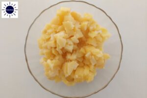 Cubed Baked Potatoes In A Glass Bowl With The Kosher Create Sun Logo In The Upper Left Corner.
