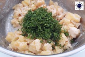 A Closeup Of The Diced Dill Added To The Salad With The Kosher Create Sun Logo In The Upper Right corner.