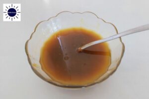 A Closeup Of The Dressing In A Glass Bowl With A Spoon With The Kosher Create Sun Logo In The Upper Left Corner.