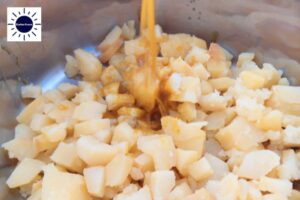 A Closeup Of The Dressing Being Poured Onto The Cubed Potatoes With The Kosher Create Sun Logo In The Upper Left Corner.