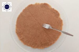 The Pie Crust In A Round Glass Dish Perforated With A Fork With The Kosher Create Sun Logo In The Upper Left Corner.