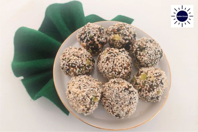 Mediterranean Wholegrain Lemony Chard Balls On A Round Plate Arranged Like A Flower With An Accordian Folded Cloth On The Left Side And The Kosher Create Sun Logo In The Upper Right Corner.