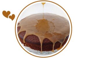Honey Orange Glaze Dripping On A Cake On A Glass Cake Stand That's Suited For Dessert In A Decorative Circle Adorned With Two Graphic Hearts On The Side.