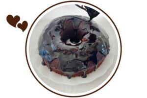 Dairy Free Maple Cocoa Glaze Dripping On A Cake On A Glass Serving Plate That's Suited For Dessert In A Decorative Circle Adorned With Two Graphic Hearts On The Side.